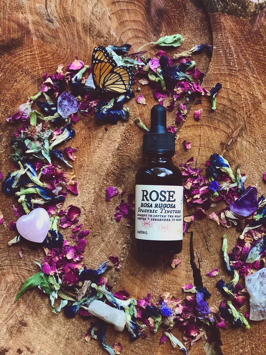 image of a rose spagyric tincture bottle lying on top of a spiral of flowers